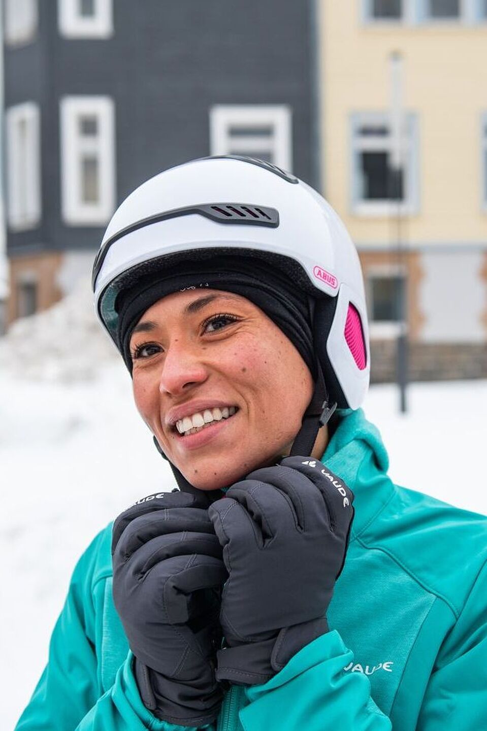 Eine dünne Mütze wärmt im Winter unter dem Helm. Frau mit Fahrradhelm im Winter mit Schnee